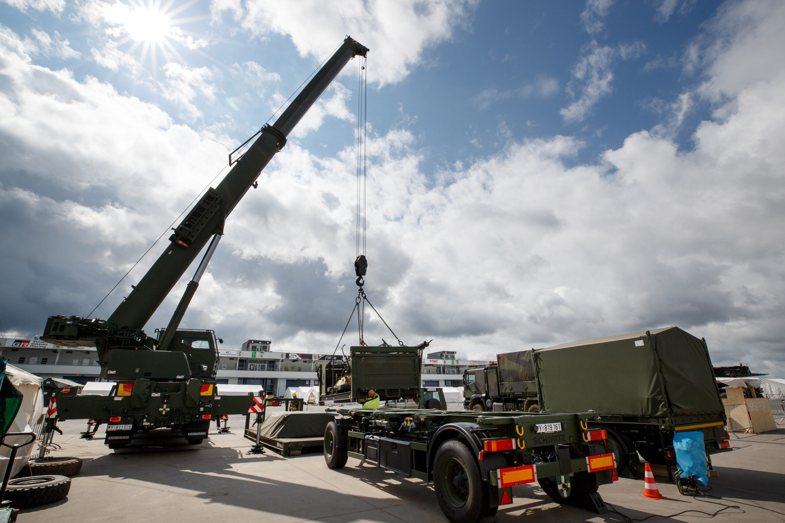 Die nun beauftragten Zwei- und Vierrad-Anhänger werden in der Bundeswehr schon lange genutzt, hier wird bspw. gerade ein Ladungsträger in Form eines Containers auf einen Vierrad-Anhänger (Vorgängerversion) aufgeladen. Blauer Bund