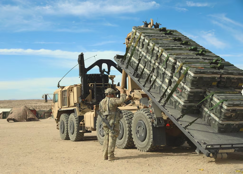 Spc. Alex Parrack assists loading Multiple Integrated Laser Engagement System equipment onto a M1075A1 Palletized Load System truck at the National Training Center on Fort Irwin, Calif. Blauer Bund